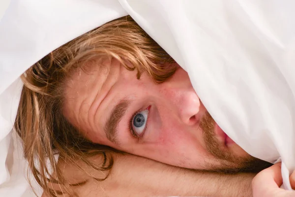 Vrolijke jongeman is na het slapen in de ochtend wakker. Knappe man met klok in bed na het ontwaken in de ochtend. Slaap wakker worden. — Stockfoto