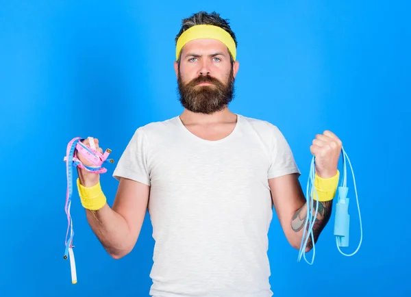 Man bearded athlete hold jump rope and tape measure. Athlete guide stay in shape. Old school aerobics concept. Athlete professional coach motivated for training. Athlete wear bandages for sweat