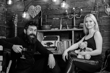 Çift gamekeepers evde, ahşap iç arka plan romantik akşamın. Rahatlatıcı kavramı. Kız ve adam mutlu yüzler üzerinde sıcak atmosferde rahatlayın. Oyuncak ayı ve mulled şarap aşık çift