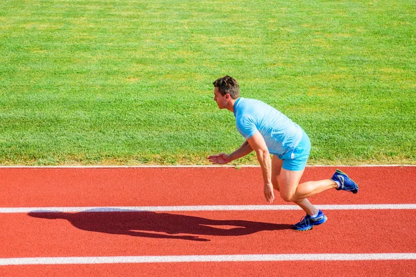 Hombre atleta corredor empujar fuera de la posición inicial del estadio camino día soleado. Corredor carrera de velocidad en el estadio. Corredor capturado en movimiento justo después del inicio de la carrera. Cómo empezar a correr. Impulsar concepto de velocidad — Foto de Stock