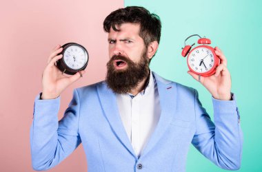 Bir adam tıraşsız şaşkın yüz zaman değişen sorunlar mı yaşıyorsunuz. Saat dilimi. Saat pislik sağlığınız ile değişen yok. Adam hipster tutun iki farklı saatler sakallı. Değişen zaman dilimleri sağlığını etkileyen