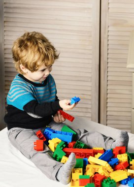 Çocuk yatağa oturur ve lego ile ahşap arka plan çalış