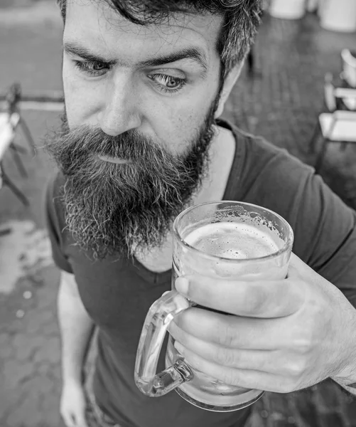 Un tipo descansando con cerveza fría. Concepto de cerveza de barril. Hombre con barba y bigote sostiene el vaso con cerveza mientras se relaja en la terraza de la cafetería. Hipster en estricta cara beber cerveza al aire libre —  Fotos de Stock