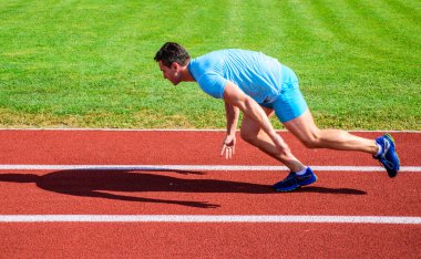 Hareket halinde sadece yarışın başlamasından sonra yakalanan koşucu. Runner sprint yarışı Stadyumu'nda. Nasıl yayınlanmaya başlaması. Alttan yukarıya ittirmek hız kavramı. Adam atlet runner itmek konum stadyum yolu güneşli gün başlamak uzakta