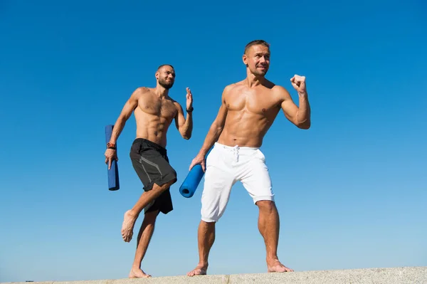 Hacia la salud. Los hombres se apresuran a practicar yoga al aire libre. Hombres musculosos entrenando al aire libre. Desarrollar fuerza muscular en el club de salud. Deporte y salud. Ejercicios diarios para mantener la salud — Foto de Stock