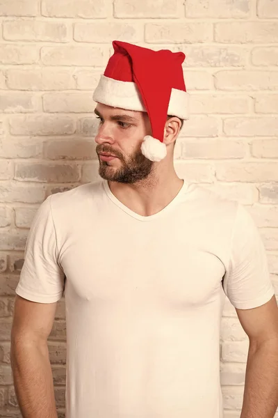 Guy with beard on serious face in red xmas hat — Stock Photo, Image