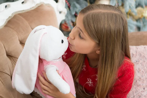 Kissable 귀 염 둥 이입니다. 작은 여자 키스 토끼 장난감입니다. 크리스마스 트리에 귀여운 토끼와 작은 소녀. 부드러운 장난감 작은 아이 놀이. 작은 아이가 현재 함께 웃 고 행복. 최고의 크리스마스 장난감 — 스톡 사진