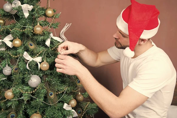 Man in santa hat decorate Christmas tree — Stock Photo, Image