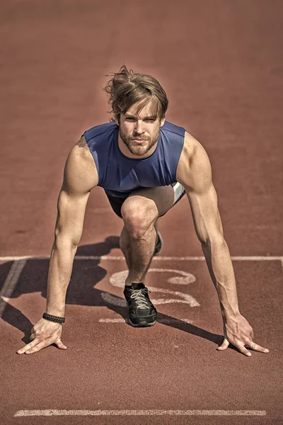 Atlético barbudo hombre con cuerpo muscular estiramiento en pista de atletismo — Foto de Stock
