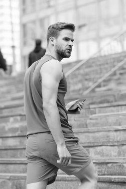 Sakallı adam akıllı telefon, merdiven ile kentsel arka plan ile yürür. Smartphone GPS navigasyon kullanan adam. GPS navigasyon kavramı. Sporcu orienteering Yarışması sırasında gezinti kullanmak