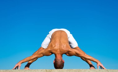 Kas vücut germe ile yoga eğitmeni. Spor ve sağlık. Koç yoga asana açık havada göstermektedir. Esnek vücut onun hak olduğunu. Zihinsel ve fiziksel sağlık. Kaslı adam denge yoga pozisyon