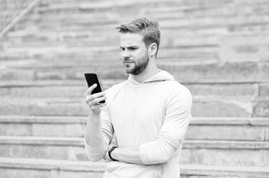 Sakallı adam akıllı telefon, merdiven ile kentsel arka plan ile yürür. Blogger'ı kullanmak smartphone akarsu video online. Adam blogger video konferans smartphone kullanarak. Blogger kavramı