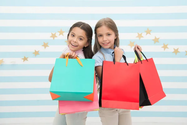 Obsesionado con centros comerciales y de ropa. Concepto de descuento. Niños chicas lindas sostienen bolsas de compras. Compras temporada de descuento. Pasando un buen rato juntos. Niños satisfecho compras rayas fondo —  Fotos de Stock