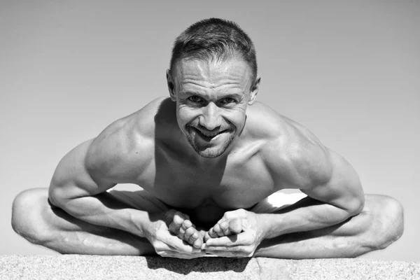 Zdrowia psychicznego i fizycznego. Muskularny mężczyzna siedzieć pozycji jogi. Instruktor jogi z rozciąganiem mięśni ciała. Sport i opieki zdrowotnej. Trener wykazać asana jogi na świeżym powietrzu. Elastyczne body jest jego zasługi — Zdjęcie stockowe