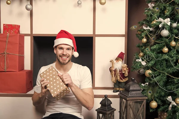 Санта-мужчина улыбается с подарочной коробкой на елке — стоковое фото