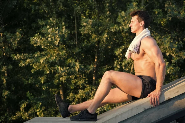 Mann mit athletischem Körper und Handtuch sitzt auf Betonfläche — Stockfoto