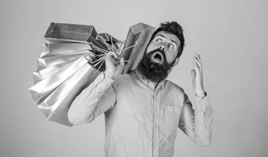 Satış ve indirim kavramı. Alışveriş satış sezonu, torba merak adam. Hipster sürpriz yüzündeki Alışverişkoliğin bağımlısı. Sakal ve bıyık taşır grup alışveriş torbaları, gri arka plan ile adam