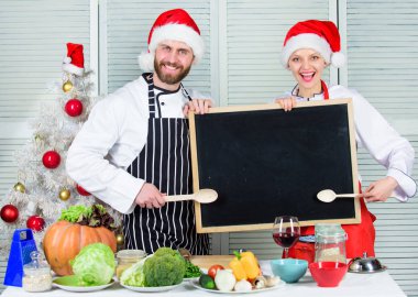 Erkek ve kadın şef santa şapka Noel ağacı yakınındaki blackboard kopya alanı tutun. Noel yemeği için aile geleneksel menü. Bizim aile için yemek listesi. Noel tarifi kavramı. Christmas yemek pişirme