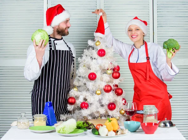 Cooking christmas meal. Man and woman chef santa hat near christmas tree. Secret ingredient is love. Christmas recipe concept. Couple preparing healthy vegetarian meal together for christmas dinner