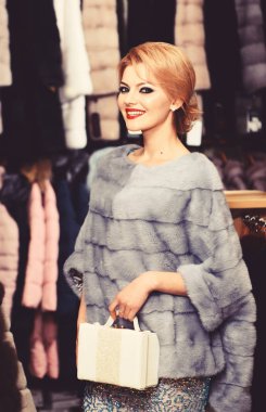 Sarı saçlı bir kadın kürklü palto alır..