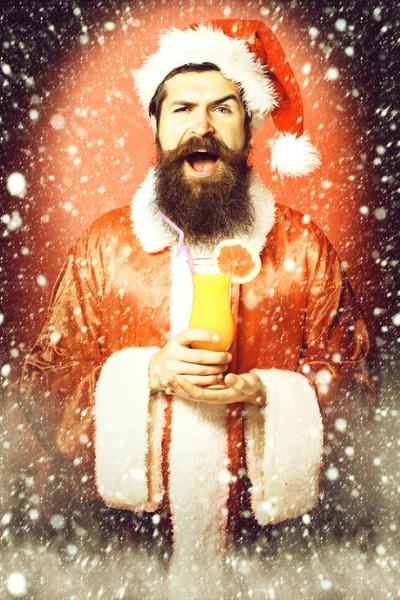 Yakışıklı, sakallı, uzun sakallı Noel Baba. Elinde Noel 'de alkolsüz kokteyl bardağı tutan uzun sakallı Noel Baba. Ya da Noel süveteri ve kırmızı stüdyo geçmişinde yeni yıl şapkası olan. — Stok fotoğraf