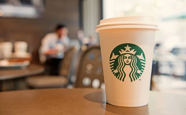 A tall Starbucks coffee cup in starbucks offee shop. — Stock Photo, Image