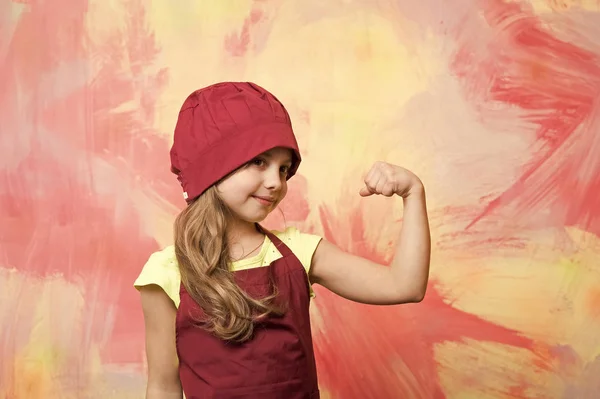Kid cook flexing hand on colorful wall