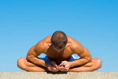 Esnek vücut onun hak olduğunu. Zihinsel ve fiziksel sağlık. Kaslı adam oturup yoga konum. Kas vücut germe ile yoga eğitmeni. Spor ve sağlık. Koç göstermek yoga asana açık havada