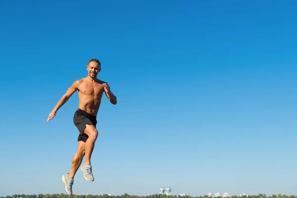 Hombre atleta musculatura torso entrenamiento al aire libre. Mañana de entrenamiento del corredor durante el amanecer. Motivación deportiva. Ejecutar hábito saludable. Movimiento corredor hacia adelante cielo espacio de copia de fondo. Mañana correr llenar de energía — Foto de Stock