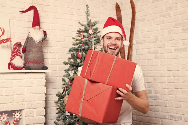 Kerst macho in rode hoed glimlach met ingepakte cadeautjes — Stockfoto