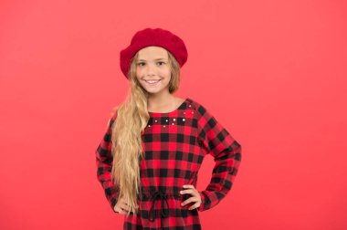 Bere tarzı ilham. Bere moda kız gibi giyin. Küçük sevimli kız bere şapka ve damalı elbise kırmızı arka plan poz uzun sarı saçlı çocuk. Erkek için şık bere aksesuar