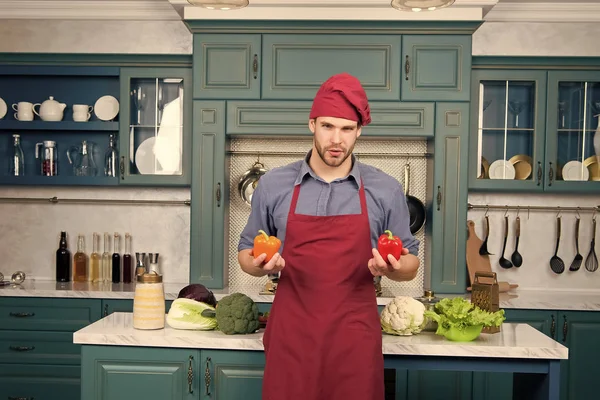 Macho in chef hat, apron with red and orange pepper — Stock Photo, Image