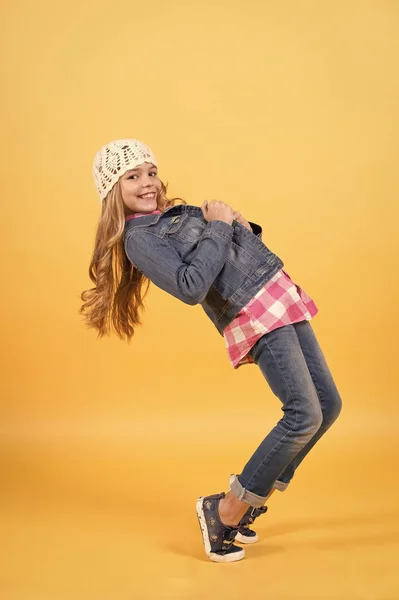 Child in jeans suit, hat, plaid shirt balance tiptoe