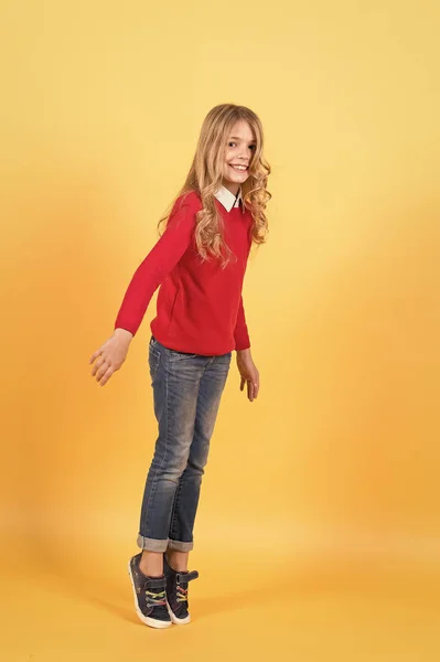 빨간 스웨터와 청바지를 입은 소녀가 발끝에 서 있다 — 스톡 사진