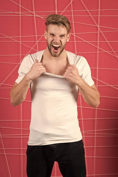 El hombre de moda tira del cuello de la camiseta con ira. Modelo de moda en estilo casual gritar sobre fondo rosa — Foto de Stock