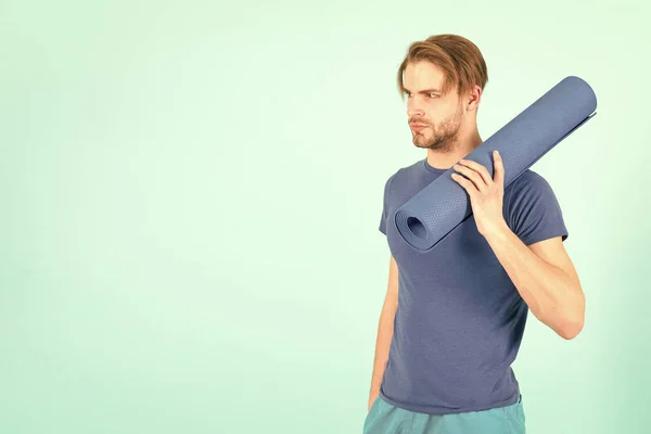 Спортсмен с синим ковриком для йоги в руке, тренажерный зал — стоковое фото