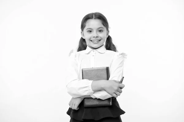 Heureuse écolière tenir livre sur fond jaune. Petite fille sourire avec manuel et stylo. Confiante en ses connaissances. Dédié à l'étude. Adorable ver de bibliothèque. Retour à l'école — Photo