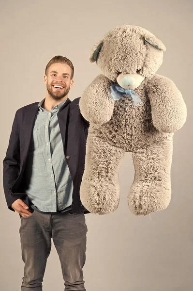Happy man with grey teddy bear, gift. Macho smiling with big animal toy, present. Gift, present concept. Birthday, anniversary, holiday celebration. valentines day