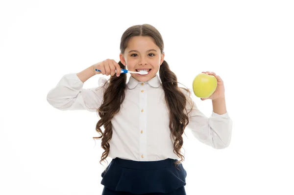 Βουρτσίζεις δόντια κάθε μέρα. Έννοια στοματικής υγιεινής. Κορίτσι κρατήσει οδοντόβουρτσα και μήλο λευκό φόντο. Παιδί κορίτσι κατέχουν φρούτα και πινέλο δόντι με πάστα. Παιδί μαθητριούλα παιδί ευτυχισμένη φροντίδα δοντιών στοματική υγιεινή — Φωτογραφία Αρχείου
