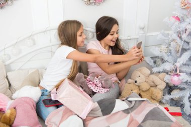 Anı yakalamak. Küçük kız yatakta smartphone kullanın. Telefonla manifatura Noel ve yeni yıl tebrik. Mutlu Noeller ve mutlu yeni yıl. Mutlu küçük çocuklar ile hareket eden telefon.