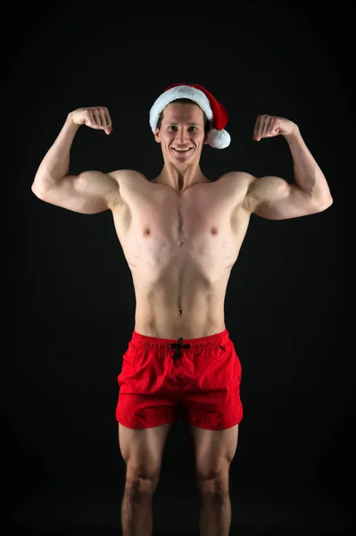 L'atleta indossa il cappello da Babbo Natale. Sexy atletica macho petto muscolare in cappello di Babbo Natale. Se tu fossi cattiva. Bel concetto di Babbo Natale. Macho busto muscolare posa con fiducia. Babbo Natale per ragazze adulte — Foto Stock