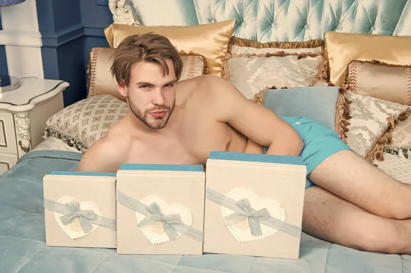 Mann mit Geschenkkartons liegt auf Bett im Schlafzimmer — Stockfoto