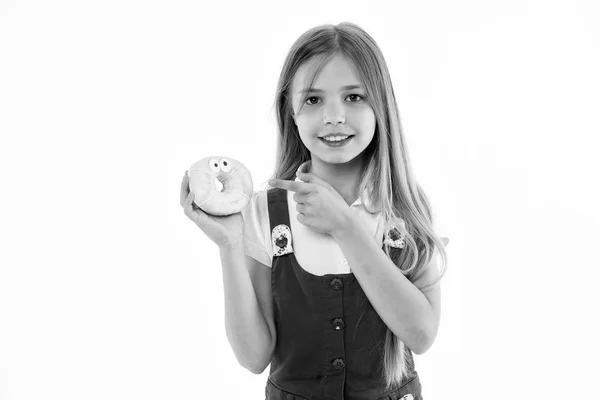 Mädchen mit breitem Lächeln und Donut in der Hand. animiertes Dessert, glasierter Bagel mit Augen. Kind zeigt auf süße Leckereien, süßer Zahn Himmel. Kind mit langen Haaren trägt rosa Outfit isoliert auf weißem Hintergrund — Stockfoto