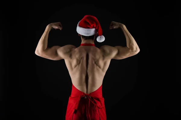 L'atleta indossa il cappello da Babbo Natale. Sexy macho atletico muscolare indietro in cappello di Babbo Natale. Bel concetto di Babbo Natale. Macho busto muscolare posa con fiducia. Babbo Natale per ragazze adulte. Forte ragazzo attraente — Foto Stock