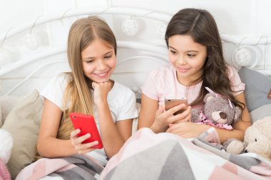 Büyük ve mutlu tatiller. Telefonla manifatura Noel ve yeni yıl tebrik. Cep telefonu ile mutlu küçük çocuklar. Küçük kız yatakta smartphone kullanın. Mutlu Noeller ve mutlu yeni yıl