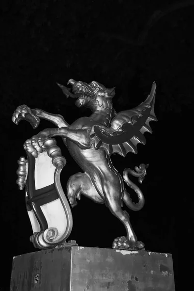 Dragon statue in London, United Kingdom. Dragon with shield on dark sky at night. Coat of arms. Famous tourist attraction. Art and design concept