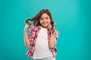 Oynak bukleler. Güzellik İpuçları derli toplu saçlar için. Çocuk kız uzun sağlıklı parlak saçlar rahat kıyafetler giymek. Uzun saçlı küçük kız. Çocuk mutlu sevimli yüzü sevimli kıvırcık saçlı mavi arka plan üzerinde durmak