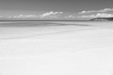 Sakin deniz plaj tropikal ada üzerinde bulutlar mavi gökyüzü. Tropik Cennet plaj kum ile. Seyahat uzmanları Antigua en iyi plajlarından ortaya koyuyor. Kum pearlescent beyaz iddia toz olarak iyi. Cennet Adası