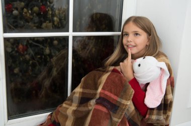 Düşüncelerinde kaybettim. Küçük çocuk Noel arifesinde sakin ol. Küçük çocuk bunny oyuncak vasıl pencere ile. Küçük kız oyuncak arkadaş tutun. Küçük kız Noel ruhu evde keyfini çıkarın. Mutlu Noeller ve mutlu yeni yıl