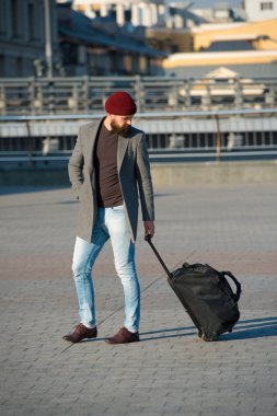 Yeni şehirde yaşayan ayarlayın. Seyahat çanta Havaalanı Tren İstasyonu kentsel arka plan gelir. Hazır hipster seyahat keyfini çıkarın. Seyahat çantası taşımak. Adam tekerlekli hipster Seyahat Bagaj çanta ile sakallı